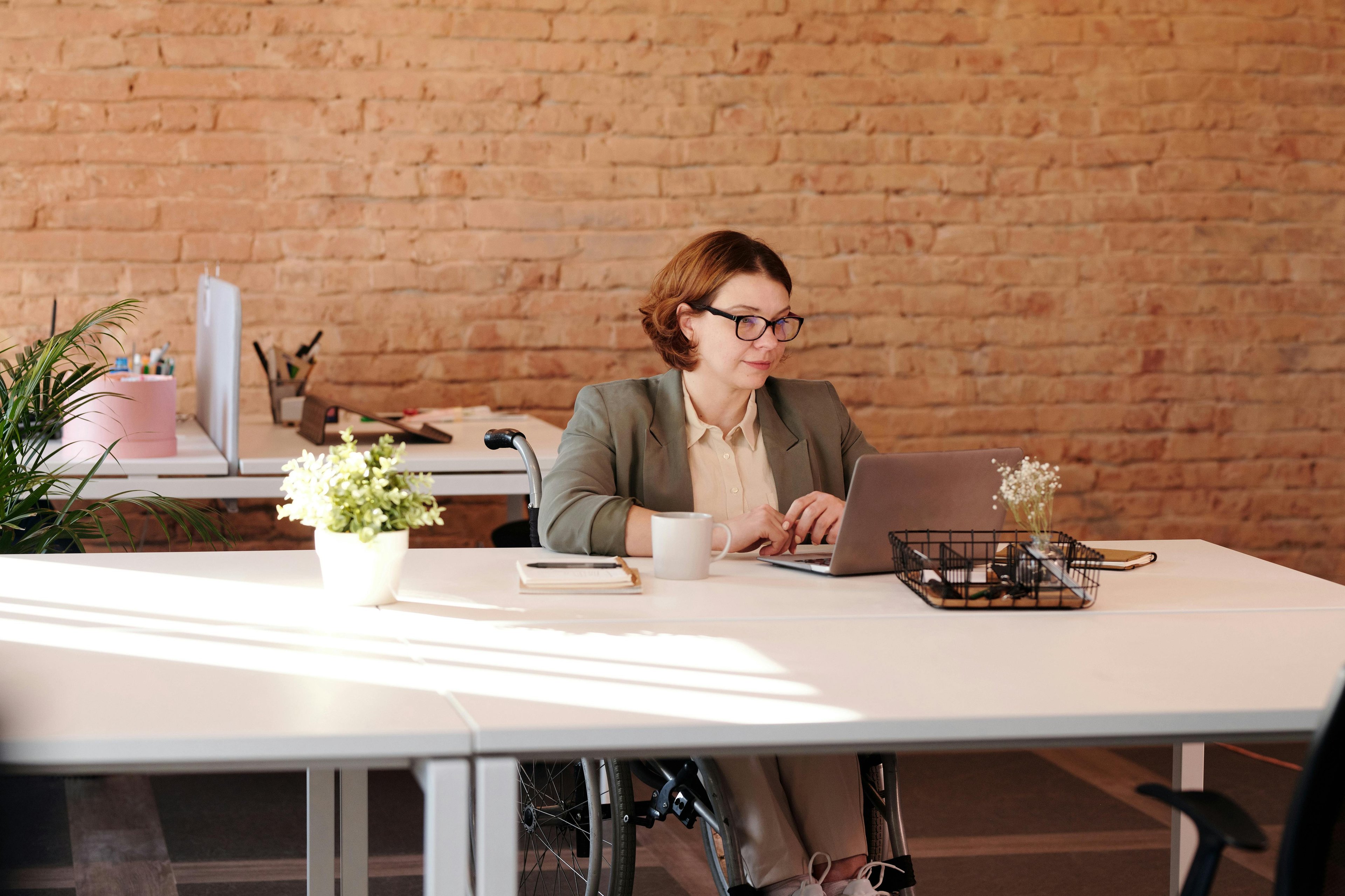 wheelchair user women at her desk working on her laptop