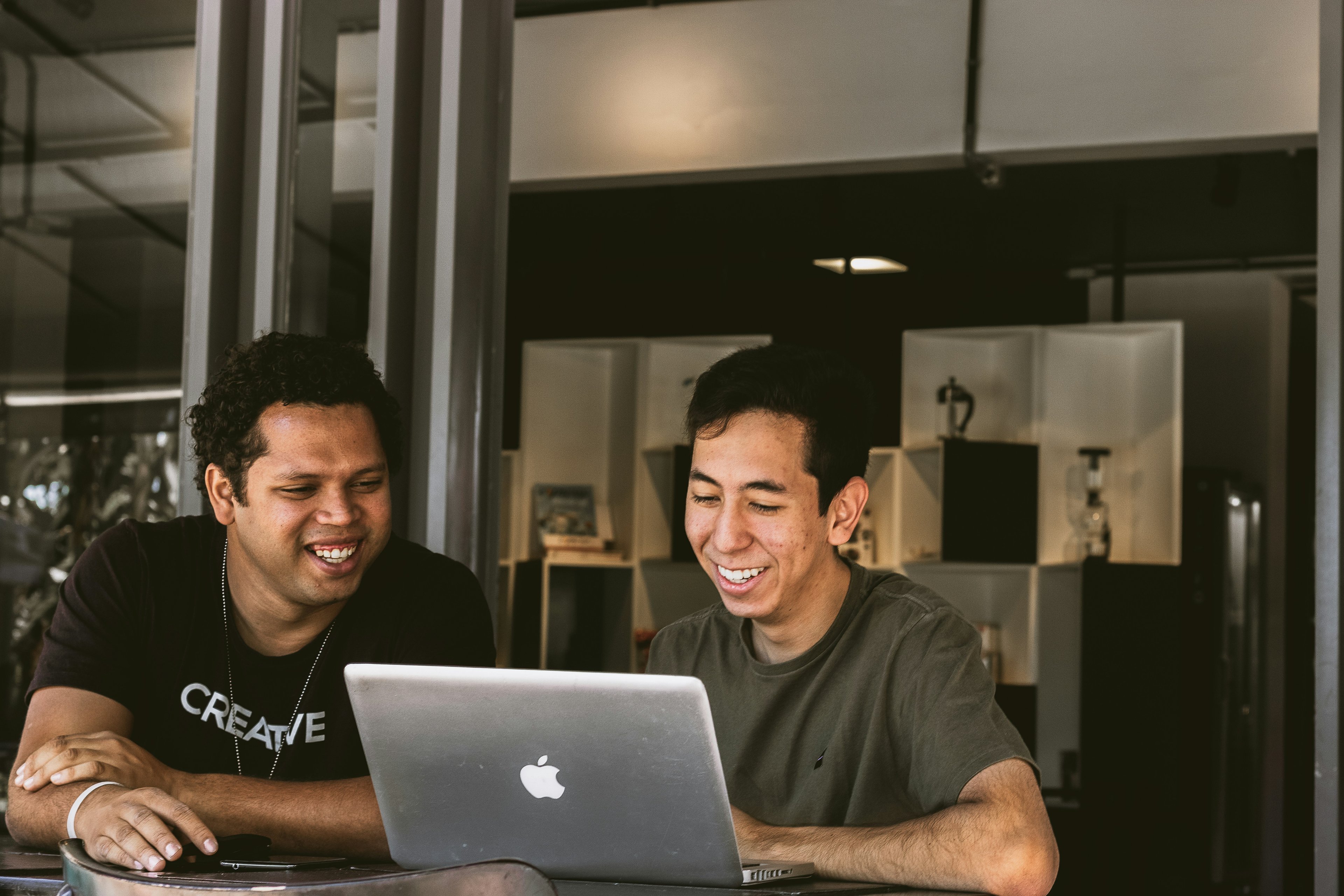 2 men sitting in front of a laptop